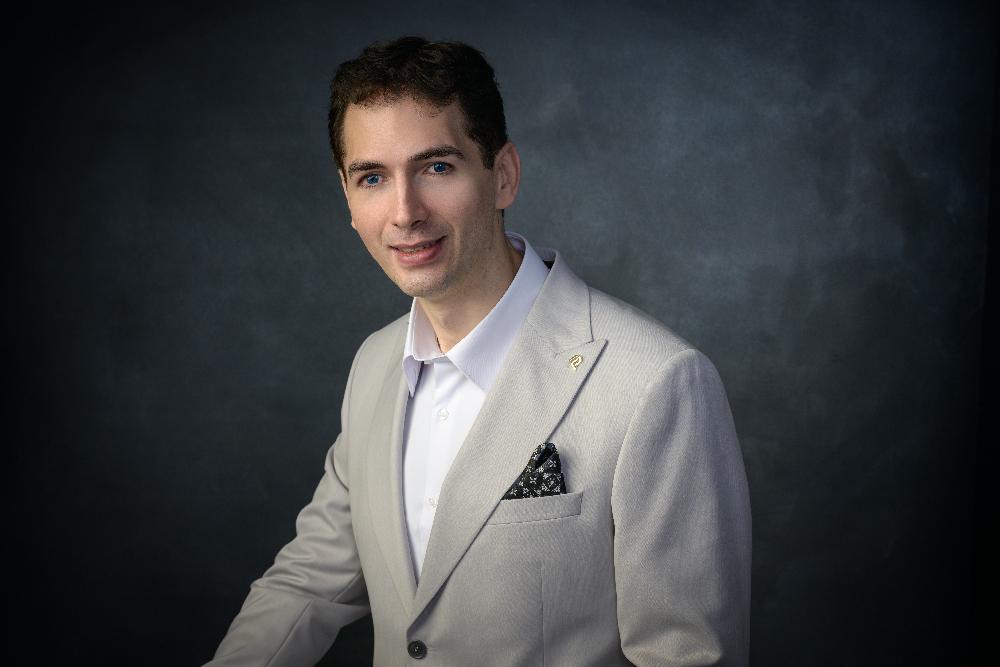 Full length formal portrait of Cristian – tall man with brown hair and blue eyes wearing a suit.