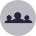 Icon including simple geometric shapes representing a group of three people in head and shoulders view.
